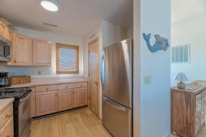 a kitchen with a stainless steel refrigerator and wooden cabinets at Into the Sun - Corolla, Villages at Ocean Hill, 75 Yds to Beach, Hot Tub, Community Pool, Pets OK, Flex Stays in Corolla +52 photos