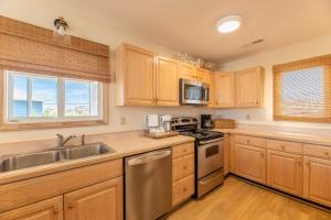 a kitchen with wooden cabinets and stainless steel appliances at Into the Sun - Corolla, Villages at Ocean Hill, 75 Yds to Beach, Hot Tub, Community Pool, Pets OK, Flex Stays in Corolla