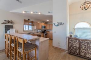 a kitchen with a large island with bar stools at Into the Sun - Corolla, Villages at Ocean Hill, 75 Yds to Beach, Hot Tub, Community Pool, Pets OK, Flex Stays in Corolla