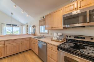 a kitchen with wooden cabinets and a stove top oven at Into the Sun - Corolla, Villages at Ocean Hill, 75 Yds to Beach, Hot Tub, Community Pool, Pets OK, Flex Stays in Corolla