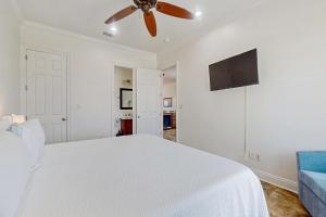 a bedroom with a white bed and a ceiling fan at Luxury Beachfront Duplex in Fort Morgan - Pool Elevator and Wedding-Friendly in Gulf Shores