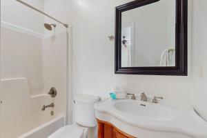a white bathroom with a sink and a mirror at Luxury Beachfront Duplex in Fort Morgan - Pool Elevator and Wedding-Friendly in Gulf Shores