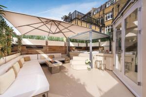 a patio with white furniture and an umbrella at MariaHilferHome in Vienna