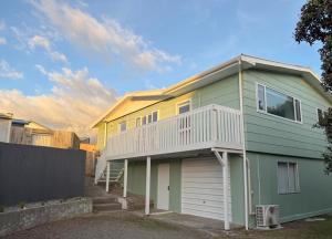 a green and white house with a garage at Waikanae Beach Abode in Waikanae