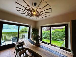 a dining room with a table and a large chandelier at La Maison Du Lac in Doussard