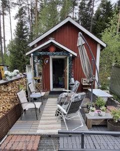 a red shed with chairs and an umbrella on a deck at B&B RhinoSauna in Vihti