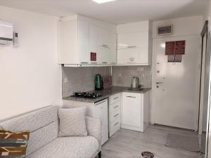 a small kitchen with white cabinets and a couch at Saklıkonak Otel in Isparta