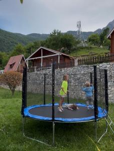 two children playing on a trampoline in a yard at Thethi Paradise Hotel & Restaurant in Theth