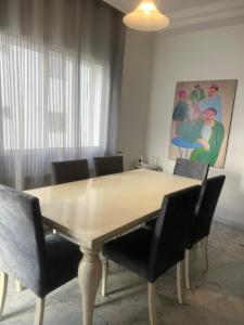a dining room table with chairs and a painting on the wall at Appartement meublé in Sukrah +6 photos