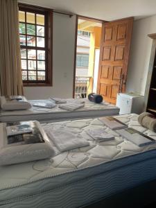 two beds sitting in a room with a window at Pousada Solar Central in Prados +11 photos