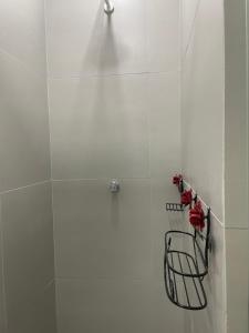 a white tiled shower with red flowers on a rack at Pousada Solar Central in Prados
