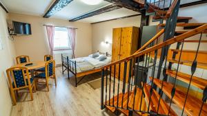 a bedroom with a bed and a table and a staircase at Penzion a Restaurace Adria II in Dobrohoř