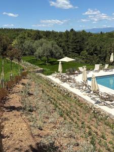 a swimming pool with umbrellas and chairs next to a resort at Castello Di Gargonza in Monte San Savino