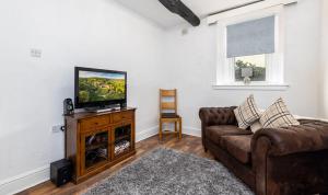 a living room with a couch and a flat screen tv at Muncaster Cottages in Ravenglass