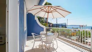 a balcony with a table and chairs and an umbrella at Hotel Vila do Farol in Bombinhas