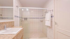 a white bathroom with a shower and a sink at Hotel Vila do Farol in Bombinhas +79 photos