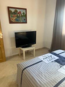 a bedroom with a flat screen tv and a bed at Appartement meublé in Sukrah