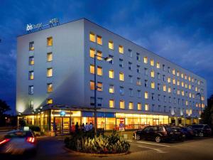 a large building with cars parked in a parking lot at ibis budget Warszawa Centrum in Warsaw