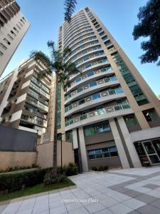 a tall building with a palm tree in front of it at Flat Moderno c/ Vista Próx. PUC, Allianz, Pacaembu in São Paulo
