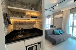 a kitchen and living room with a sink and a couch at Flat Moderno c/ Vista Próx. PUC, Allianz, Pacaembu in São Paulo