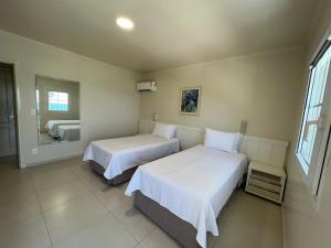 a bedroom with two beds and a mirror in it at Hotel Vila do Farol in Bombinhas