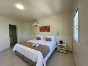 a bedroom with a large bed and a window at Hotel Vila do Farol in Bombinhas