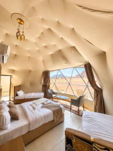 a bedroom with two beds and a large window at Wadi Rum Faris in Wadi Rum