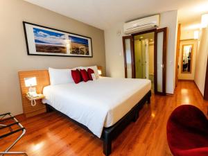 a bedroom with a large white bed with red pillows at Novotel Lima San Isidro in Lima