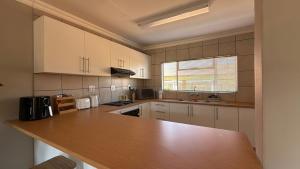 a kitchen with white cabinets and a wooden counter top at The Pebbles-Unit-1 in Mahikeng