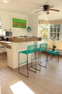 a kitchen with four chairs and a bar with a counter at Isla Lorens in Isla Mujeres