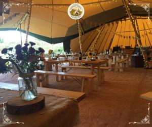 a tent with wooden tables and flowers in a vase at Edinburgh Festival Glamping By Stay Social Stays in Edinburgh