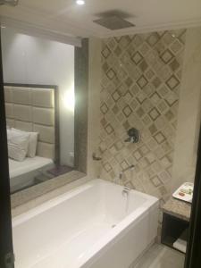 a bathroom with a bath tub and a mirror at Shiva Oasis Resort in Neemrana