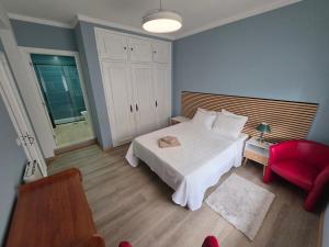 a bedroom with a white bed and a red chair at Quinta da Mainça in Coimbra