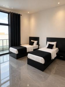 two beds in a room with a large window at Ohio villa in Sowayma +25 photos