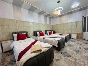 a room with three beds with red pillows at Yangi Andijan Hotel in Andijan