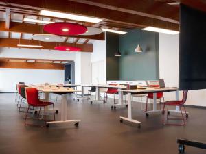 a conference room with tables and chairs and a screen at Ibis Pontarlier in Pontarlier