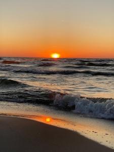 a sunset on the beach with the ocean at Domki u Rybaka in Kąty Rybackie +4 photos