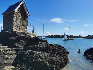 a person swimming in the water next to a stone wall at Plage du Pont - Chambres d'Hôtes in Saint Malo