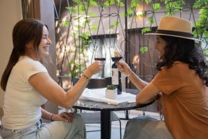 two women sitting at a table with glasses of wine at Atelier Petit Hotel in Ciudad Lujan de Cuyo