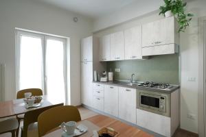 a kitchen with white cabinets and a table and a dining room at La Terrazza del benessere in Ferrazzano