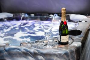 a bottle of champagne and a glass in a tub at HOTEL Villa Cvijanović - WELLNESS-SPA in Palić