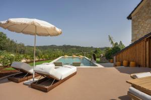 a pool with two lounge chairs and an umbrella at BaguHouse in Pombal