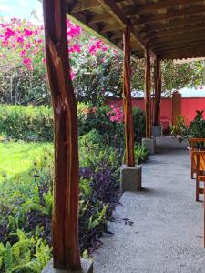 a wooden pergola in a garden with pink flowers at Cabinas Marcelina in Puerto Jiménez