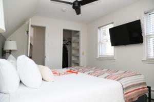 a white bedroom with a bed and a flat screen tv at Mercury Hotel Provincetown in Provincetown +37 photos