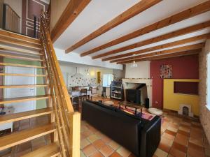 a living room with a black couch and a fireplace at Le Gîte du Moulin in Saint-Maigrin