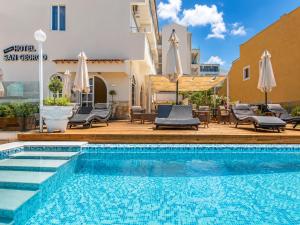 a pool with chairs and umbrellas next to a building at San Georgio Hotel in Agios Georgios Pagon