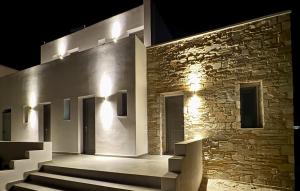 a building with stairs and a stone wall with lights at AiΘeria Suites Ios in Ios Chora