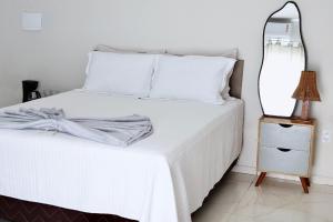 a bedroom with a white bed and a mirror on a night stand at Suite Areal in Atins +11 photos