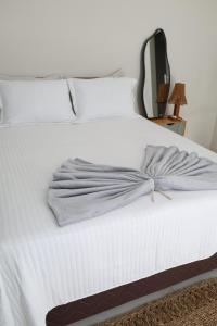 a bedroom with a white bed with a towel on it at Suite Areal in Atins