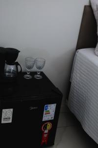 two wine glasses on a table next to a bed at Suite Areal in Atins